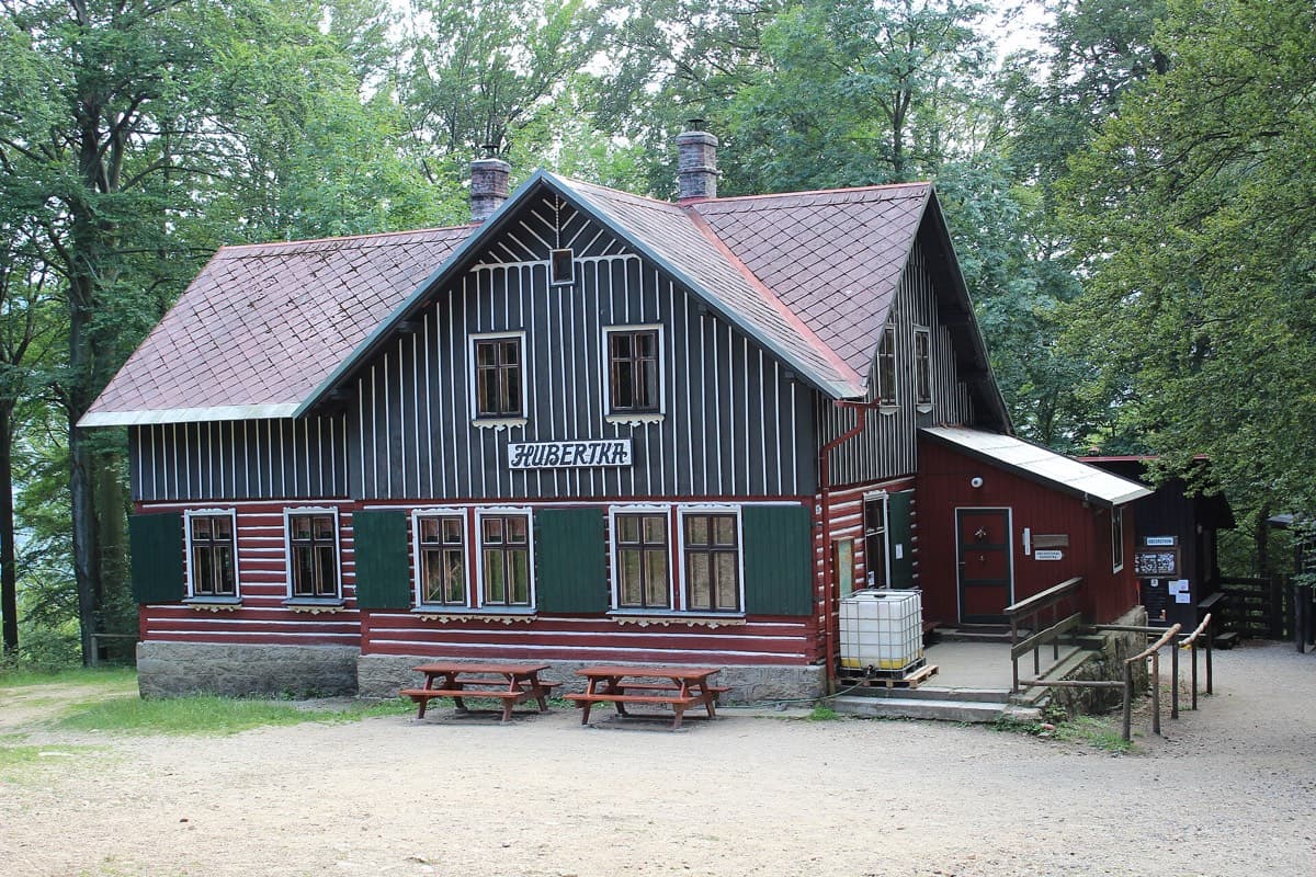 Horská chata s dřevěným štítem a lavicemi před vstupem